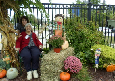 Two women pose outside by seasonal autumn decorations