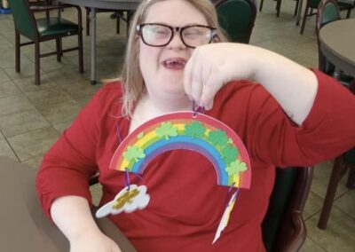A woman holds up her rainbow-themed St. Patrick's Day craft