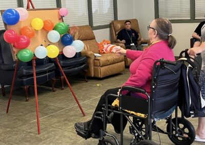 A woman throws darts at a balloon board